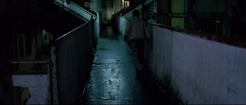 Movie still from “Gomorrah” (2008), directed by Matteo Garrone – A man walking down a long hallway at night; Wide shot, High angle
