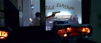 Movie still from “Gomorrah” (2008), directed by Matteo Garrone – A man holding a gun in front of a window; Medium shot, Low angle