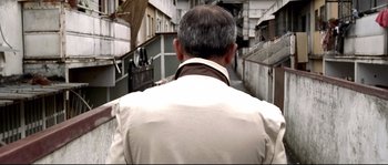 Movie still from “Gomorrah” (2008), directed by Matteo Garrone – A man wearing a white jacket walking down a street; Medium shot, Low angle