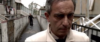 Movie still from “Gomorrah” (2008), directed by Matteo Garrone – A person wearing a suit and tie; Medium shot, Over the shoulder angle