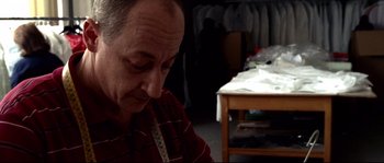 Movie still from “Gomorrah” (2008), directed by Matteo Garrone – A man sitting in front of a sewing table; Medium shot, Low angle