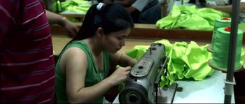 Movie still from “Gomorrah” (2008), directed by Matteo Garrone – A woman working on a sewing machine in a room; Medium shot, High angle