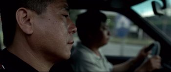 Movie still from “Gomorrah” (2008), directed by Matteo Garrone – A man sitting in the passenger seat of a car; Close Up shot, Low angle