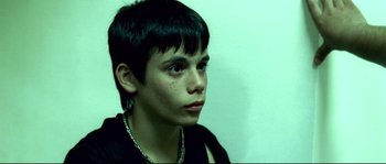 Movie still from “Gomorrah” (2008), directed by Matteo Garrone – A young man with short black hair looking to his left; Close Up shot, High angle