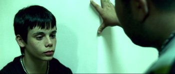 Movie still from “Gomorrah” (2008), directed by Matteo Garrone – A man pointing to a wall while a boy looks on; Close Up shot, Over the shoulder angle