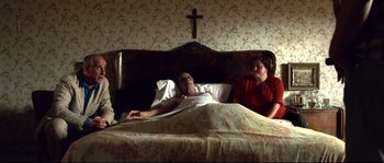 Movie still from “Gomorrah” (2008), directed by Matteo Garrone – An old man laying in a bed next to a woman; Wide shot, High angle
