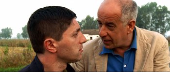 Movie still from “Gomorrah” (2008), directed by Matteo Garrone – A man and a man standing next to each other; Close Up shot, Over the shoulder angle