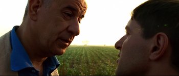 Movie still from “Gomorrah” (2008), directed by Matteo Garrone – Two men are talking in front of an open field; Close Up shot, Low angle