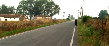 Movie still from “Gomorrah” (2008), directed by Matteo Garrone – A man riding a bike down a street; Extreme Wide shot, High angle