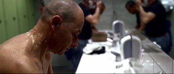 Movie still from “Gomorrah” (2008), directed by Matteo Garrone – A bald man sitting at a bathroom sink; Close Up shot, Over the shoulder angle
