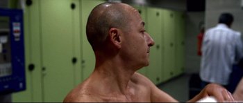 Movie still from “Gomorrah” (2008), directed by Matteo Garrone – A man with a shaved head is standing in a room; Close Up shot, Over the shoulder angle