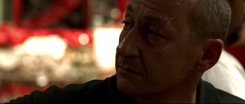 Movie still from “Gomorrah” (2008), directed by Matteo Garrone – An older man looking into the distance with a serious look; Close Up shot, Over the shoulder angle