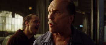 Movie still from “Gone in 60 Seconds” (2000), directed by Dominic Sena – A man with a mustache and a beard is looking at the camera while a man with a mustache and a beard is standing next to him; Close Up shot, Low angle