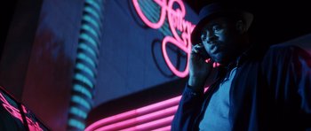 Movie still from “Gone in 60 Seconds” (2000), directed by Dominic Sena – A man talking on a cell phone in front of a neon sign; Close Up shot, Low angle