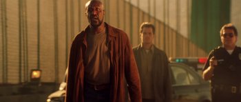 Movie still from “Gone in 60 Seconds” (2000), directed by Dominic Sena – Two men are standing in a dimly lit room; Medium shot, Low angle