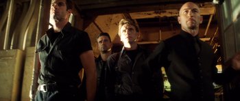 Movie still from “Gone in 60 Seconds” (2000), directed by Dominic Sena – A group of men standing next to each other in a room; Medium shot, Low angle