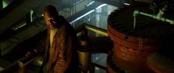 Movie still from “Gone in 60 Seconds” (2000), directed by Dominic Sena – A man sitting next to a fire hydrant in an industrial setting; Medium shot, Low angle