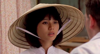 Movie still from “Good Morning, Vietnam” (1987), directed by Barry Levinson – A woman wearing a straw hat and a white shirt; Close Up shot, Low angle