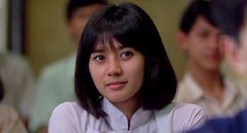 Movie still from “Good Morning, Vietnam” (1987), directed by Barry Levinson – A young woman with black hair wearing a white shirt; Close Up shot, Over the shoulder angle