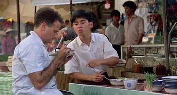 Movie still from “Good Morning, Vietnam” (1987), directed by Barry Levinson – A man and a woman sitting at an outdoor table; Medium shot, Over the shoulder angle