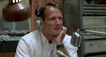 Movie still from “Good Morning, Vietnam” (1987), directed by Barry Levinson – A man wearing headphones and a microphone; Close Up shot, Low angle