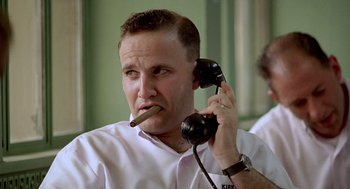 Movie still from “Good Morning, Vietnam” (1987), directed by Barry Levinson – A man smoking a cigarette while holding a phone to his ear; Close Up shot, Low angle
