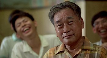 Movie still from “Good Morning, Vietnam” (1987), directed by Barry Levinson – An older man and a younger man are smiling for the camera; Close Up shot, Over the shoulder angle