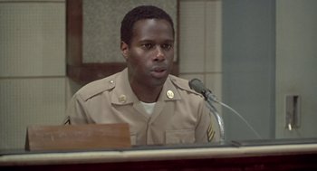 Movie still from “Good Morning, Vietnam” (1987), directed by Barry Levinson – A man in a military uniform sitting in front of a microphone; Close Up shot, Low angle