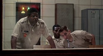 Movie still from “Good Morning, Vietnam” (1987), directed by Barry Levinson – A group of men sitting in front of microphones in a room; Medium shot, Low angle