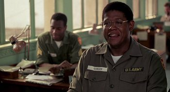 Movie still from “Good Morning, Vietnam” (1987), directed by Barry Levinson – Two men sitting at a table in front of each other; Close Up shot, Low angle