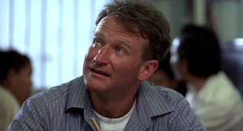 Movie still from “Good Morning, Vietnam” (1987), directed by Barry Levinson – A person sitting down with his mouth open; Close Up shot, Low angle