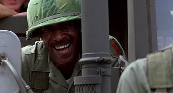 Movie still from “Good Morning, Vietnam” (1987), directed by Barry Levinson – A man in a military uniform smiles at the camera; Close Up shot, Low angle