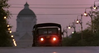 Movie still from “Good Morning, Vietnam” (1987), directed by Barry Levinson – A bus driving down a street at night; Extreme Wide shot, Low angle