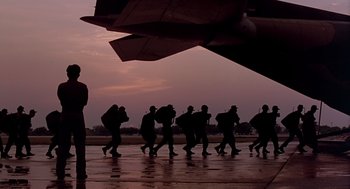 Movie still from “Good Morning, Vietnam” (1987), directed by Barry Levinson – A group of people walking across a wet runway; Wide shot, Low angle