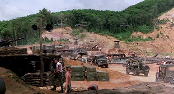 Movie still from “Good Morning, Vietnam” (1987), directed by Barry Levinson – A group of men standing on top of a dirt field; Extreme Wide shot, High angle