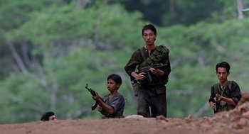 Movie still from “Good Morning, Vietnam” (1987), directed by Barry Levinson – Two young men are standing on a hill holding guns; Medium shot, Low angle