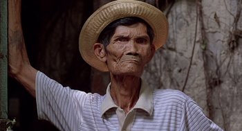 Movie still from “Good Morning, Vietnam” (1987), directed by Barry Levinson – An old man wearing a straw hat and a striped shirt; Close Up shot, Low angle