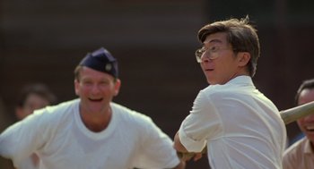 Movie still from “Good Morning, Vietnam” (1987), directed by Barry Levinson – A man swinging a baseball bat while another man watches; Close Up shot, Low angle