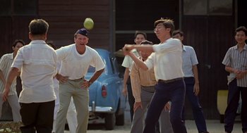 Movie still from “Good Morning, Vietnam” (1987), directed by Barry Levinson – A group of men playing a game of baseball; Medium shot, Over the shoulder angle