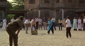 Movie still from “Good Morning, Vietnam” (1987), directed by Barry Levinson – A group of people standing in the sand playing a game; Wide shot, Over the shoulder angle
