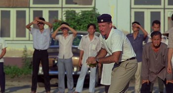 Movie still from “Good Morning, Vietnam” (1987), directed by Barry Levinson – A group of men standing next to each other on the street; Medium shot, Over the shoulder angle