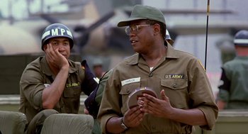 Movie still from “Good Morning, Vietnam” (1987), directed by Barry Levinson – A man in a military uniform talking on a cell phone; Medium shot, Low angle