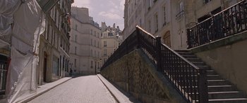 Movie still from “To the Wonder” (2012), directed by Terrence Malick – A sidewalk with a railing on the side of a building; Extreme Wide shot, High angle