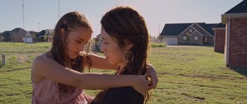Movie still from “To the Wonder” (2012), directed by Terrence Malick – A young girl hugging a woman in a grassy field; Close Up shot, Over the shoulder angle