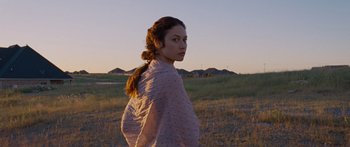 Movie still from “To the Wonder” (2012), directed by Terrence Malick – A woman standing in a grassy field with her head turned to the side; Medium shot, Over the shoulder angle