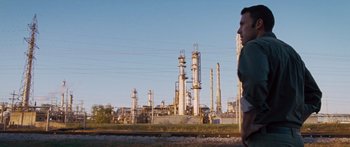 Movie still from “To the Wonder” (2012), directed by Terrence Malick – A man standing on a train track in front of an oil refinery; Wide shot, Low angle