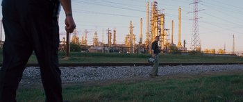 Movie still from “To the Wonder” (2012), directed by Terrence Malick – A man walking on a train track near an oil refinery; Extreme Wide shot, Low angle