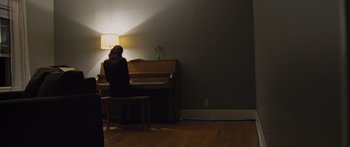Movie still from “To the Wonder” (2012), directed by Terrence Malick – A person sitting at a piano in a room; Wide shot, High angle