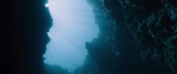 Movie still from “To the Wonder” (2012), directed by Terrence Malick – The sun shines through the water on the bottom of a cliff; Extreme Wide shot, Overhead angle