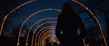 Movie still from “To the Wonder” (2012), directed by Terrence Malick – A woman standing in front of an arch of lights at night; Wide shot, Low angle